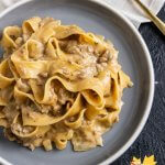 a serving of the finished pasta with parpadelle on a grey plate, on top of a beige plaid tea towel