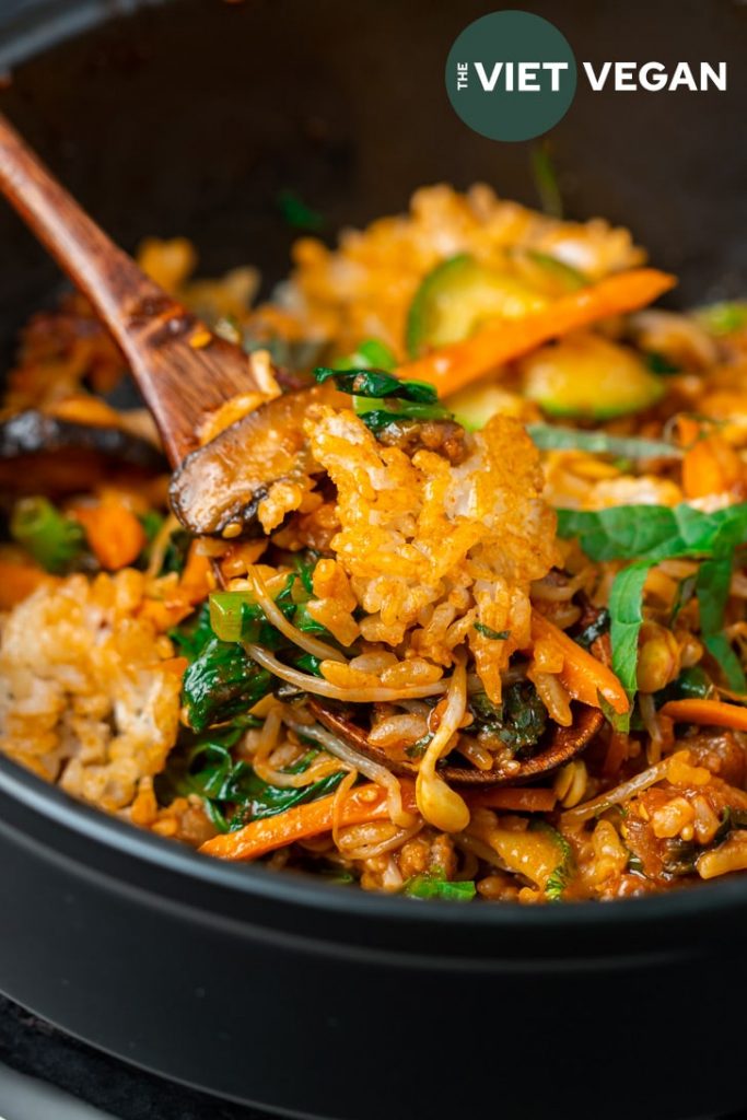 mixed rice on a spoon resting above the bowl of dolsot bibimbap