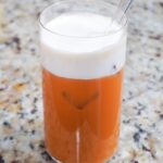 vegan thai iced tea in a glass with a layer of vegan cheese foam on top