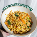 vegan stir fry in a white bowl in front of a white sheer curtain